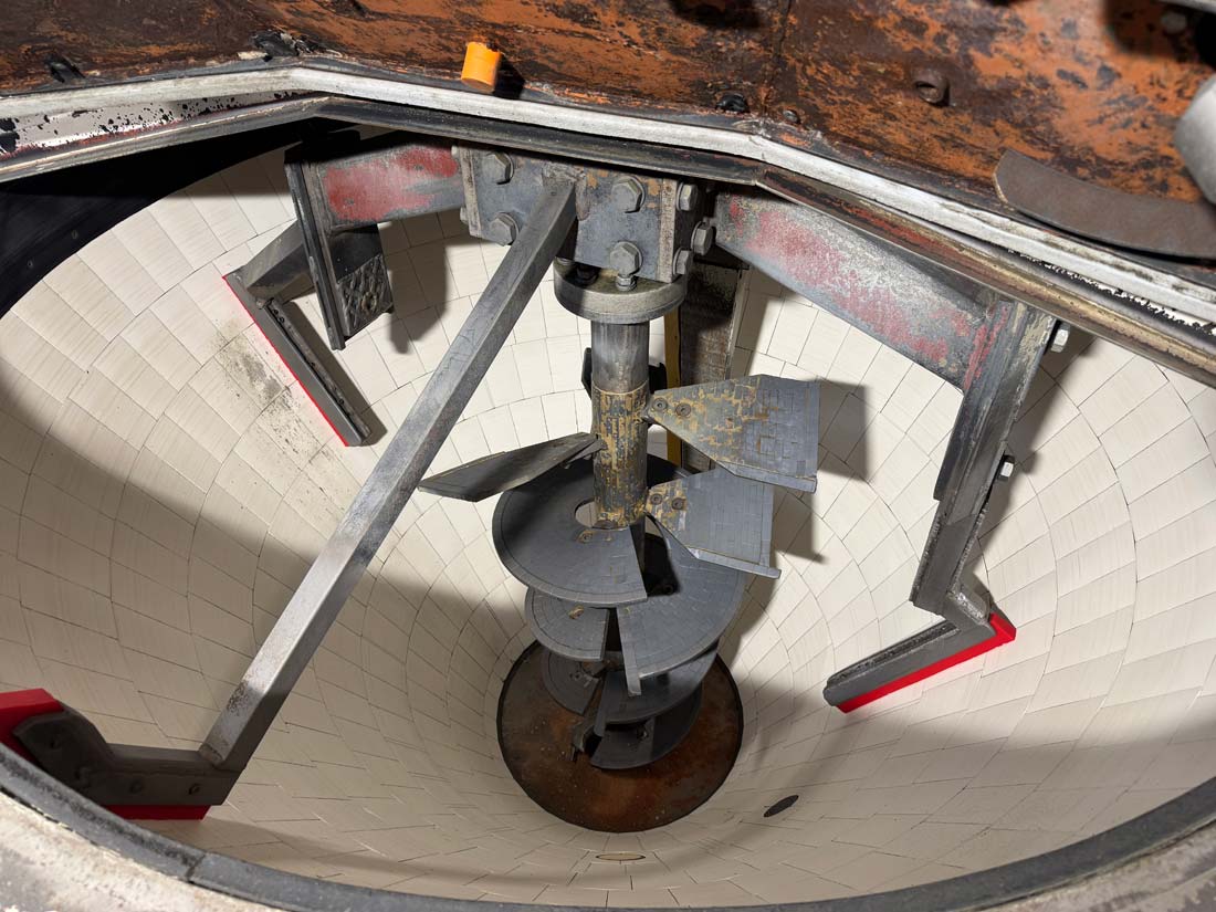 Weißer Beton ausgehärtet in mehreren Bahnen aufeinander gedruckt in Form eines Blumentopfs mit Wellen.